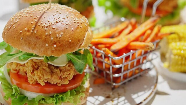 Crispy, breaded chicken double burgers with vegetables and drink, served with sweet potatoes