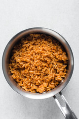 Jollof rice in a silver saucepan, homemade nigerian jollof rice in a pot, overhead view of authentic homemade west african jollof rice