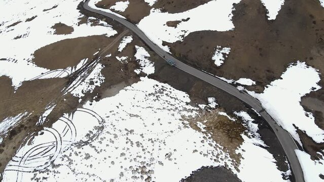 aerial view of snowy ice high mountains road with car driving on  world's highest village hikkim in spiti valley in himachal pradesh