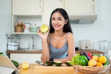 A woman shows an avocado to the camera while she prepares her healthy meals in the kitchen.