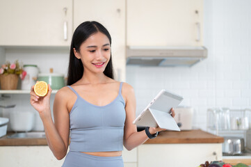 A beautiful Asian woman is searching for healthy recipes online on her tablet in the kitchen.