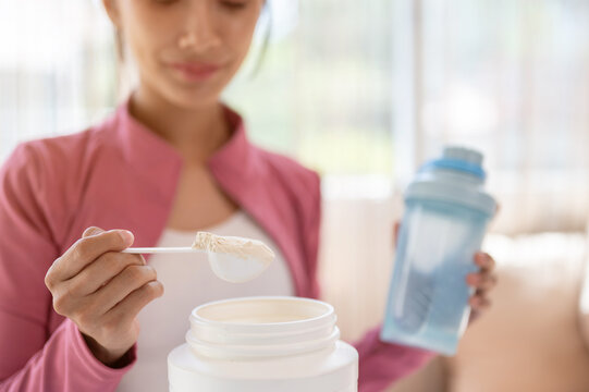 Close-up image of a healthy Asian woman in sportswear making her protein shake after a workout.
