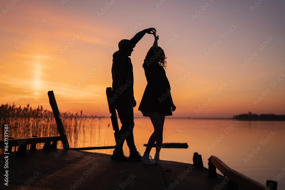 Wall mural Couple dancing at sunset salsa / brazilian zouk. Lovers, dance partners spinning, latin festival dance concept.