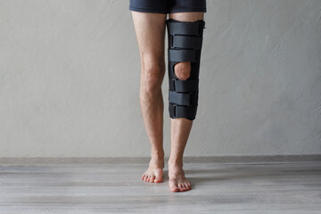Patient standing with knee brace support after do posterior cruciate ligament surgery. Healthcare and medical concept. - obrazy, fototapety, plakaty