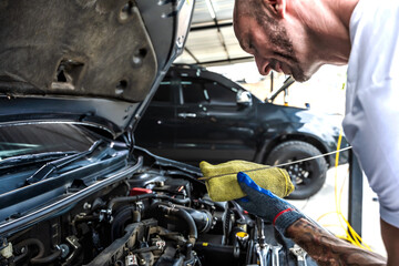 Auto mechanic checking car engine oil in repair garage
