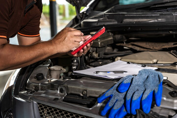 Obraz premium Auto mechanic using battery tester working in auto repair