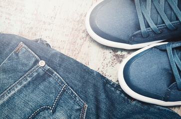 Pair of jeans thrown on floor with a pair of sneakers