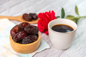 Dried dates fruit in wooden bowl with a cup of coffee.