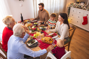 Family holding hands and praying before Christmas dinner at home