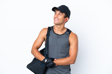 Young sport caucasian man with sport bag isolated on white background looking up while smiling