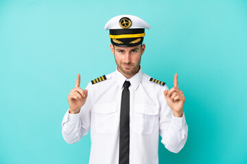 Airplane caucasian pilot isolated on blue background pointing up a great idea