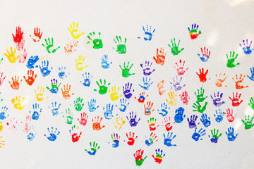 Pattern of colorful handprints was stamped on a white wall with colored children hands
