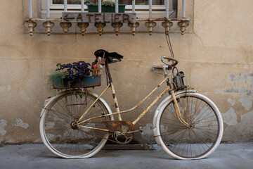 Nancy, France - 09 02 2023: View of an old rusty decorative bike placed against a wall in the city center. - obrazy, fototapety, plakaty