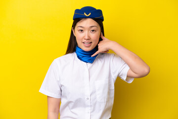 Airplane Chinese woman stewardess isolated on yellow background making phone gesture. Call me back sign