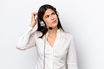 Telemarketer caucasian woman working with a headset isolated on white background having doubts and...
