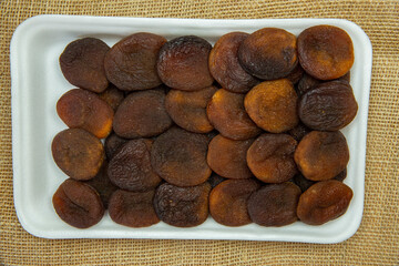 Sun dried apricot on rock plate in white foam top view