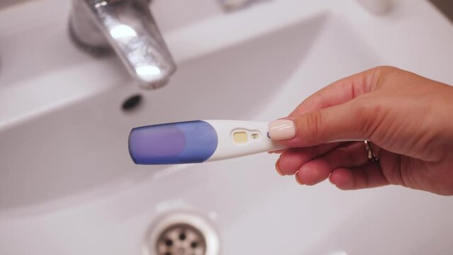 Woman with anxious feelings. Girl with a negative pregnancy test. Close-up of hands holding pregnancy test.