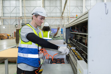 Staff worker man using Compressor Air Blow Gun cleans dust in machine. Male working cleaning...