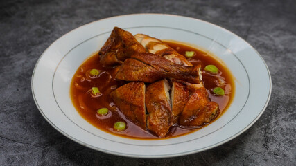 Cantonese-style chicken with sauce served in a plate placed on the table