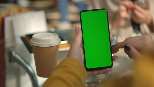 Use green screen for copy space closeup. Chroma key mock-up on smartphone in hand. Woman holds mobile phone and swipes photos or pictures left indoors of cozy home