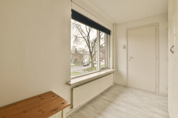 an empty room with a bench and window looking out onto the street in front of the house on a sunny day