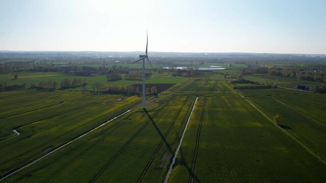 High Up Aerial view of Single Wind Turbine Roratng Blands Standing in Agricultural Crop Field 