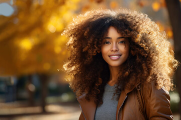 Young smiling african woman walking at park in autumn morning