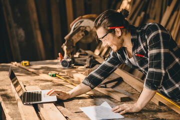 Carpenter man using modern technology computer laptop software aided sketch design new wooden...