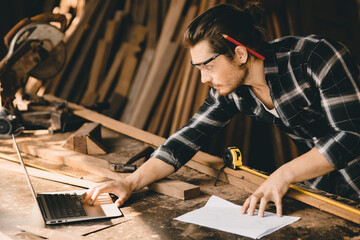 Carpenter man using modern technology computer laptop software aided sketch design new wooden...