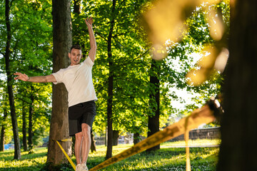 Sportsman on the rope practising slacklining and looking concentrated
