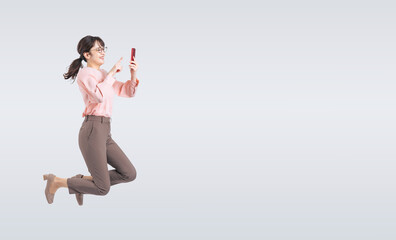 スマホを使いながらジャンプするミドル女性（切り抜き背景透過PNGも販売しております。作成者リンクから「PNG」で検索してください）