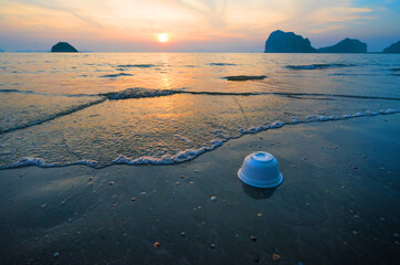 Styrofoam cup on tropical beach  pollutes the sea and marine life. Garbage rubbish trash problem...