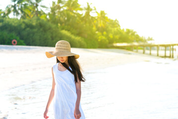 Portrait of young Asian girl walking on white sand beach with mangrove tree. Teenager girl wearing...