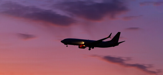 plane flies at dusk against the backdrop of a beautiful sunset sky
