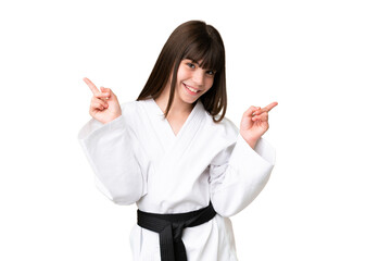 Little Caucasian girl doing karate over isolated background pointing finger to the laterals and...