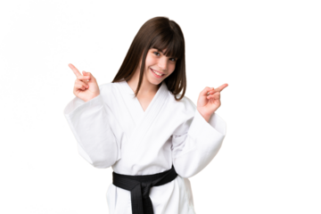 Little Caucasian girl doing karate over isolated background pointing finger to the laterals and happy
