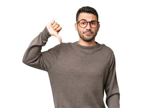 Young handsome caucasian man over isolated background showing thumb down with negative expression