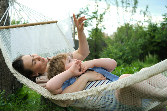 Summer Serenity: Amidst the gentle sway of a hammock, a mother and her young son share cherished conversations and hugs, epitomizing the joys of summer bonding