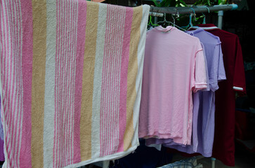 old towel and t-shirt dry outdoors by rack and hangers