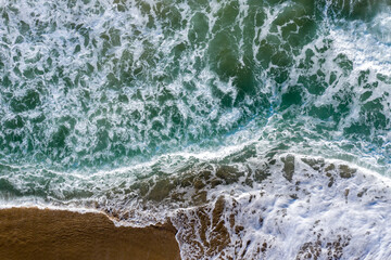 Aerial view of wild sea waves crushing the beach