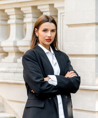 young business woman posing outside with smartphone and laptop, against wall, column, leaking from...