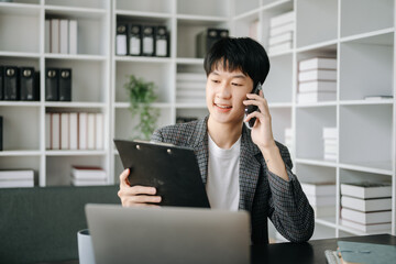 Young business man working at modern office with laptop, tablet and taking notes on the paper..