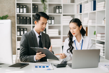 Two business workers talking on the smartphone and using laptop at the office.