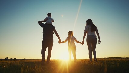 people in the park. happy family walking silhouette at sunset. mom dad and daughters walk holding hands in the park. happy family childhood dream concept. parents and children sun go back silhouette