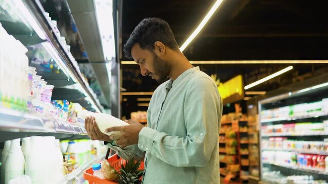 Side view of handsome indian man buying milk. A man shopping dairy product in grocery store