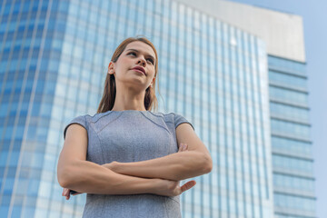Portrait of a young and successful white caucasian business woman standing in front of a modern cityscape of office buildings