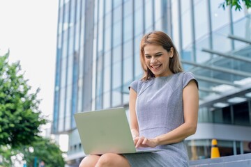 Young caucasian businesswoman working remotely outside her office building 