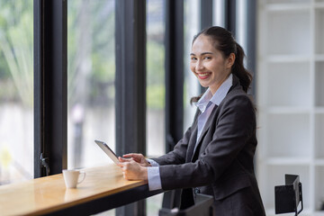 Young Asian business woman using tablet and taking notes in workplace office