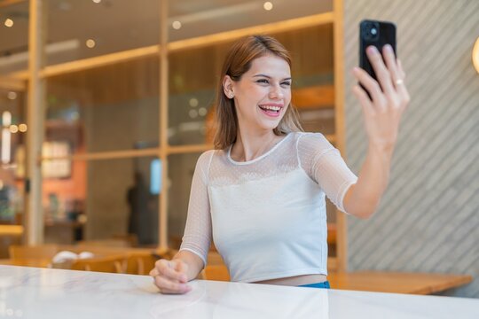 Young woman using smartphone to selfie in a cafe