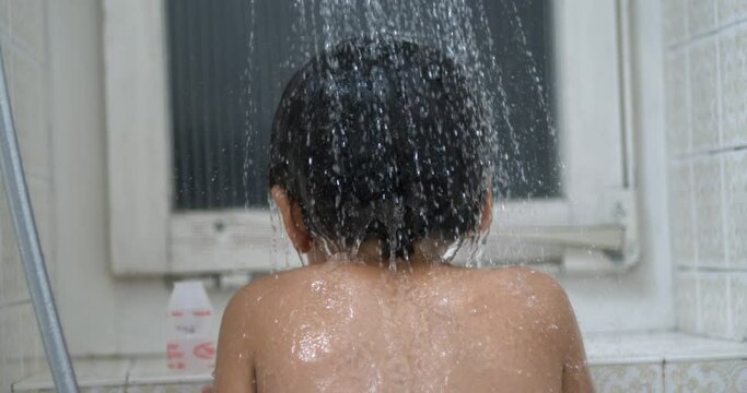 Back of child with water flower in super ultra slow-motion 800 fps. bathing kid underneath shower head